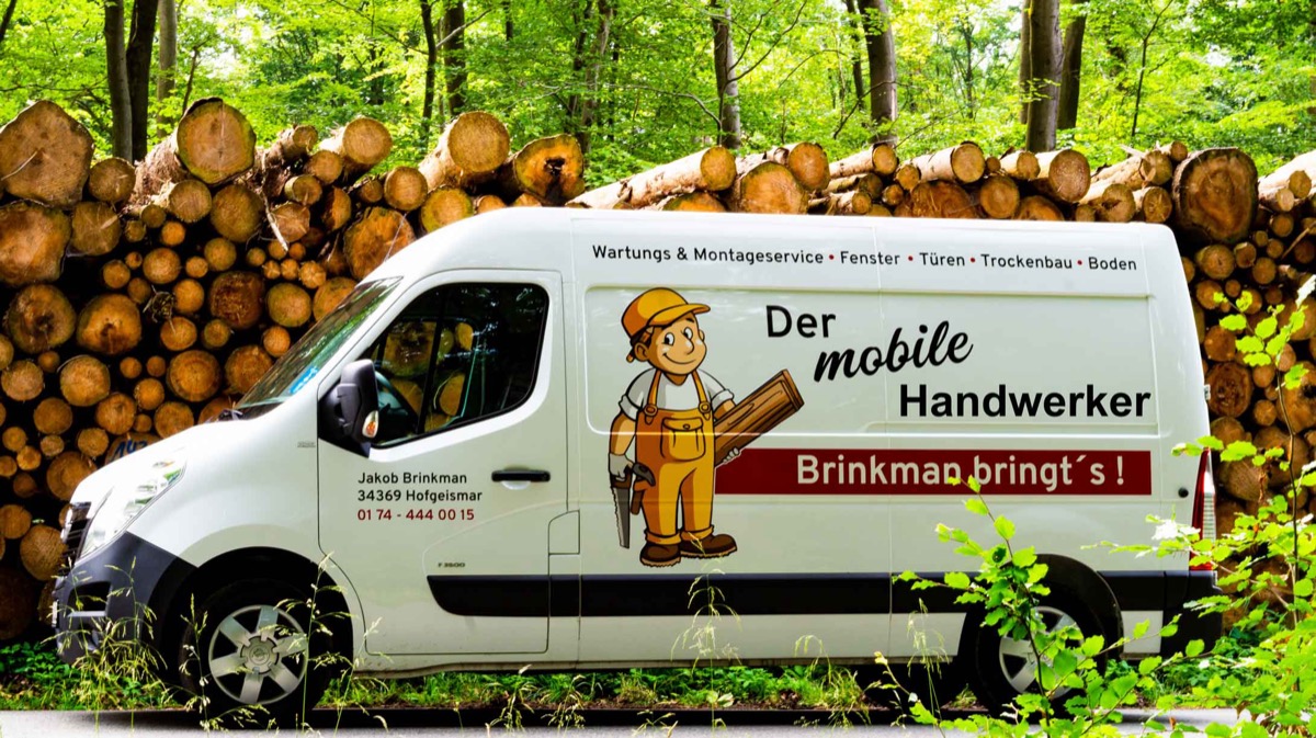 Der Servicewagen von brinkman bringt's mit Handwerker-Motiv, geparkt vor gestapeltem Holz im Wald in Nordhessen